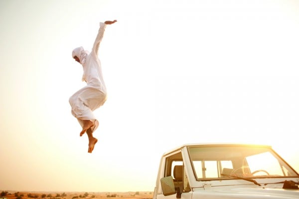 An Middle Eastern Culture youth on a quad bike in the desert.