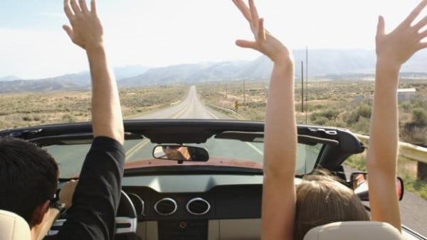 Couple in car with hands in air